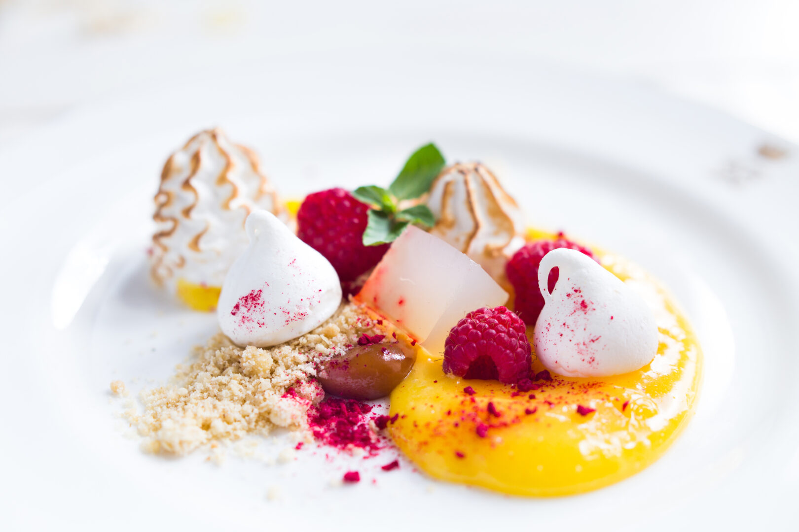 A dessert plate filled with fresh raspberries, meringue and lemons
